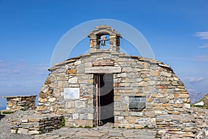 A scenics view of a mountain summit with a chapel under a majestic blue sky and some white clouds