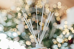 Scent of Christmas. Diffuser with sticks with aroma of vanilla, oranges and cinnamon on Christmas shining tree