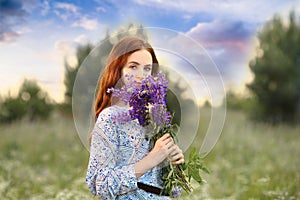 Scent of flowers concept. Young girl holding a bouquet of lilac flowers near her face. Floristry and flowers. Copy space