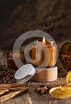 Scented candle in a glass jar. Coffee aroma. Star anise, cinnamon sticks, dried orange. Still life. Coffee beans. Brown