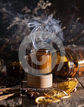 Scented candle in a glass jar. Coffee aroma. Star anise, cinnamon sticks, dried orange. Still life. Coffee beans. Brown