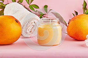 Scented candle for Spa and home with a mango scent and green leaves on a pink background