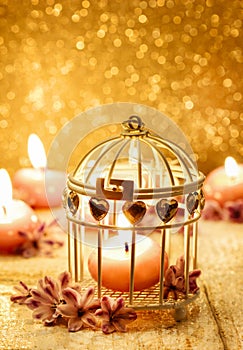 Scented candle in vintage birdcage. Golden background