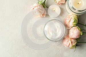 Scented candles, cosmetic cream and roses on white table