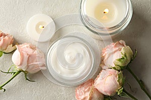 Scented candles, cosmetic cream and roses on white table
