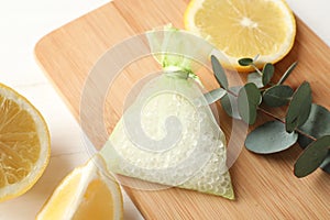 Scented sachet with aroma beads, eucalyptus branch and lemon on white wooden table, closeup