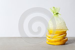 Scented sachet with aroma beads and slices of lemon on grey table, space for text