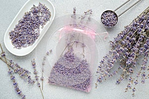 Scented sachet and dried lavender flowers on light gray textured table, flat lay