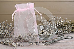Scented sachet with dried lavender flowers and scissors on wooden table