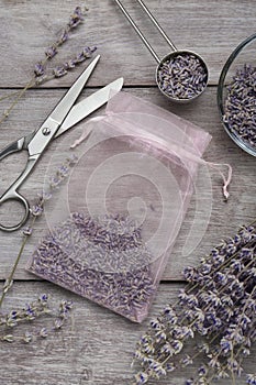 Scented sachet with dried lavender flowers and scissors on wooden table, flat lay