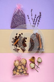 Scented sachets with dried flowers, coffee beans and spices on color background, flat lay