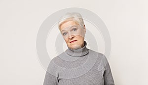 Sceprical senior woman over light stidio background