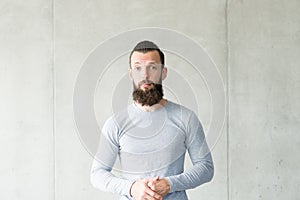 Sceptic bearded hipster guy gray wall background