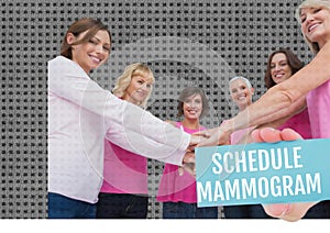 Schedule mammogram text banner over group of caucasian women stacking their hands together