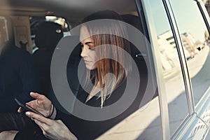 Scheduling her work appoints the smart way. a young businesswoman using a mobile phone while traveling in a car.