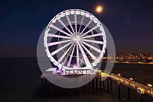 Scheveningen, the Hague illuminated ferris wheel on the pier at night under moonlight