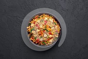 Schezwan Chicken Fried Rice in black bowl at dark slate background. indo-chinese cuisine dish