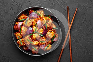 Schezwan Paneer in black bowl at dark slate background. Schezwan Paneer is indo-chinese cuisine dish