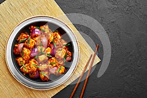 Schezwan Paneer in black bowl at dark slate background. Schezwan Paneer is indo-chinese cuisine dish