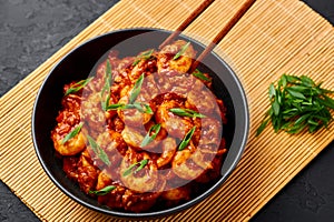 Schezwan Prawns in black bowl at dark slate background. Schezwan Prawns is indo-chinese cuisine curry dish