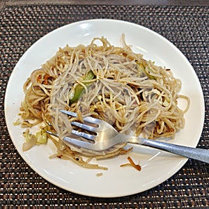 Schezwan or vegetable Hakka Noodles or chow mein is a popular Indo-Chinese recipes, served in a bowl or plate with fork. photo