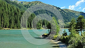 Schlierersee, Lungau Austria.Mountain lake and mountains covered with pine trees on blue sky background.Beautiful