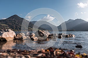 The Schliersee in autumn colors in the Bavarian mountains. With blurred autumn leaves in the foreground.