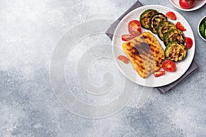 Schnitzel of chicken and zucchini cooked on the grill. Fresh tomatoes on a plate. Ready delicious dinner lunch. Copy space