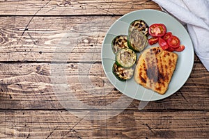 Schnitzel of chicken and zucchini cooked on the grill. Fresh tomatoes on a plate. Ready delicious dinner lunch. Wooden background