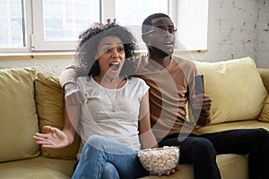 Schocked african family couple watching thriller on tv