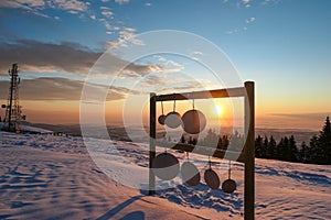 Schoeckl - A wooden frame with round plates hanging from it located at the top of snow covered peak of Schoeckl, Austrian Alps