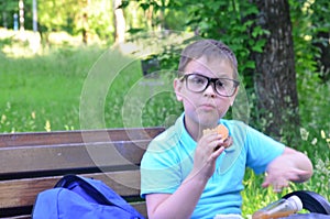 Scholl boy Adorable little boy sitting on the bench with lunchbox in park. Healthy food and snacks for kids. Child