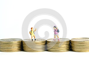 School admission budget.  Children or kids, walking above golden coin money stack. Miniature tiny people toys photography.