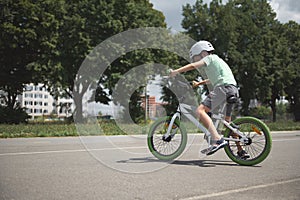 A school-age boy learns extreme tricks and extreme cycling in the city. Sporty child in protective gear riding a bicycle