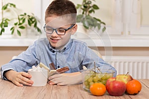 The school-age boy smiles and holds a dish with sweets and a sugar bowl with sugar cubes. Next to it, on the table top are mandari