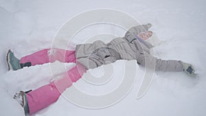 A school-age child crawls with pleasure in the snowdrifts. Harsh winter and a lot of snow. The child plays in the snow