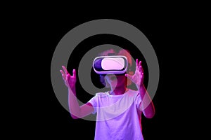 School age girl wearing white t-shirt enjoying 3D technology in virtual reality headset isolated on dark background in