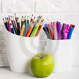 School background: a white brick wall with accessories, pencils, tetrads, scissors, an apple, pecans, a board for a