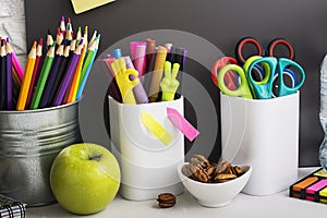 School background: a white brick wall with accessories, pencils, tetrads, scissors, an apple, pecans, a board for a