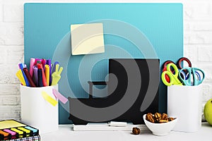 School background: a white brick wall with accessories, pencils, tetrads, scissors, an apple, pecans, a board for a