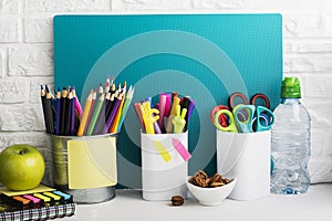 School background: a white brick wall with accessories, pencils, tetrads, scissors, an apple, pecans, a board for a
