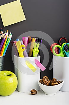 School background: a white brick wall with accessories, pencils, tetrads, scissors, an apple, pecans, a board for a