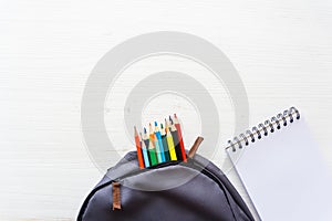 School bag, color pencil and notebook on white wooden table. Back to school concept