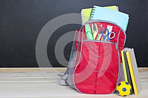 School bag rucksack supplies wooden blackboard background.