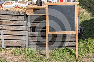 School board with space for text or logo stands on the grass against a background of old wooden pallets.