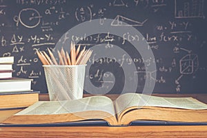 School books on desk formulas and Physics inscription on the blackboard , education concept