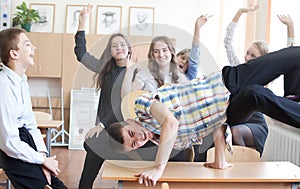 School boy doing back flip on the desk in the classroom . Sunny