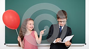 School boy and girl child with balloon on chalkboard background having fun