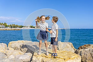 School boy and girl jumping on a rocks near sea. After school activities.