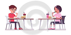 School boy, girl sitting at desk eating lunch in canteen